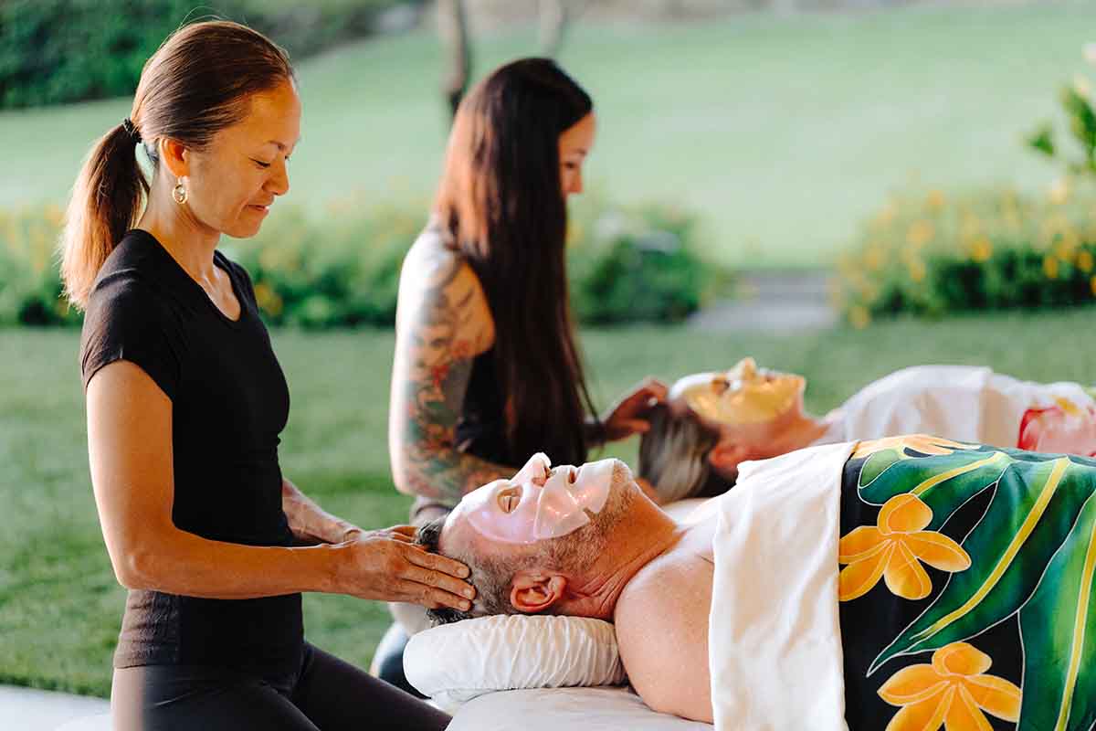 A couple receiving a collagen face mask add-on service during a mobile massage therapy